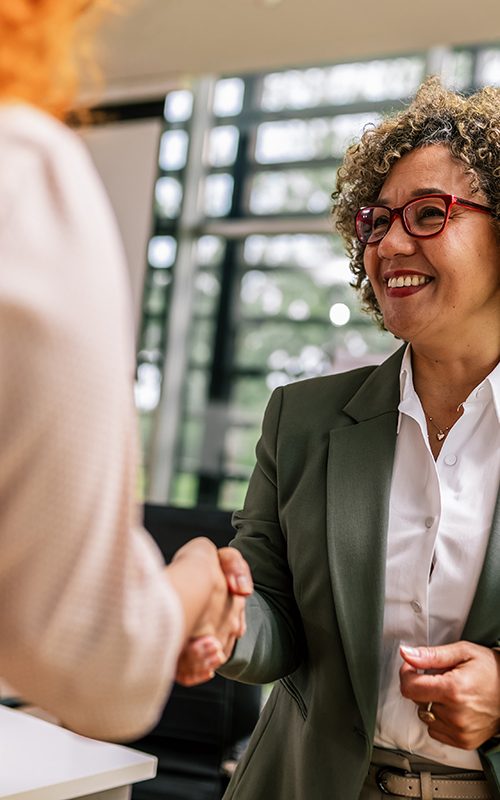 African American woman from Human Resource congratulates the new ginger employee of their company after the job interview.